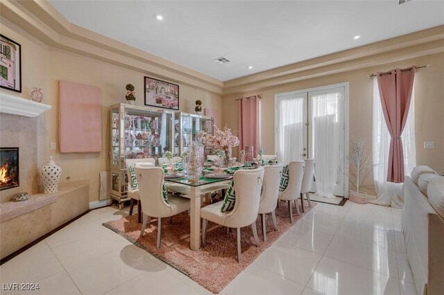 dining space with light tile patterned floors, a fireplace, and french doors