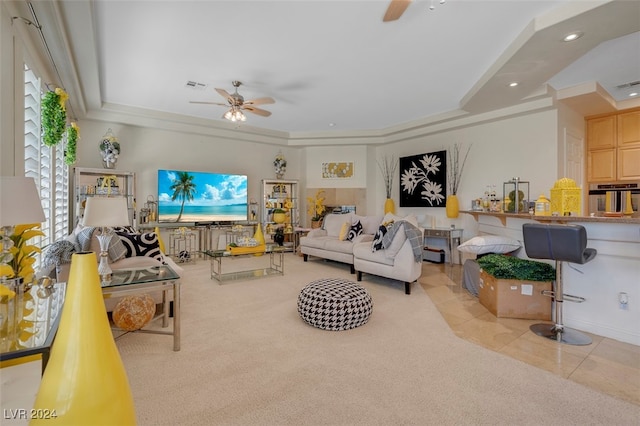 living room with ceiling fan, a raised ceiling, and light colored carpet