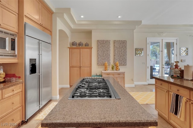 kitchen featuring built in appliances, light brown cabinetry, and a kitchen island