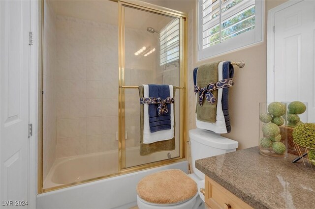 full bathroom with vanity, shower / bath combination with glass door, and toilet