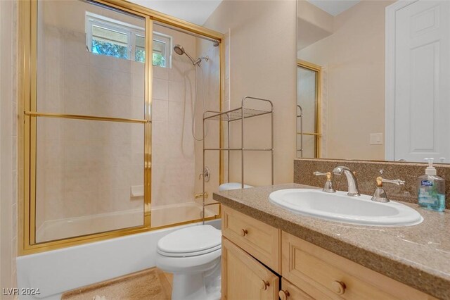 full bathroom featuring vanity, bath / shower combo with glass door, and toilet