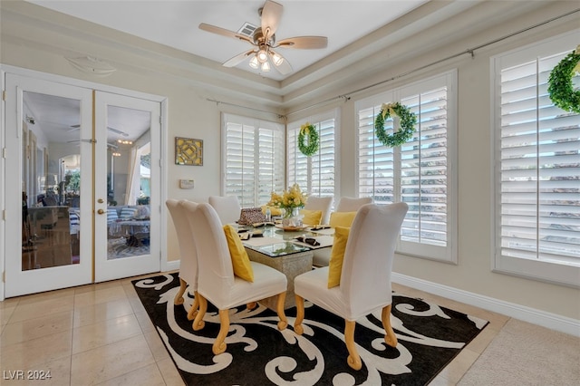 dining area featuring french doors, ceiling fan, a raised ceiling, and light tile patterned floors