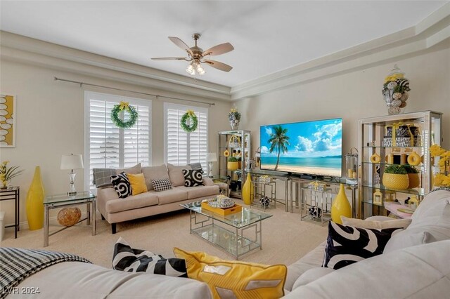 living room featuring a tray ceiling, light colored carpet, and ceiling fan