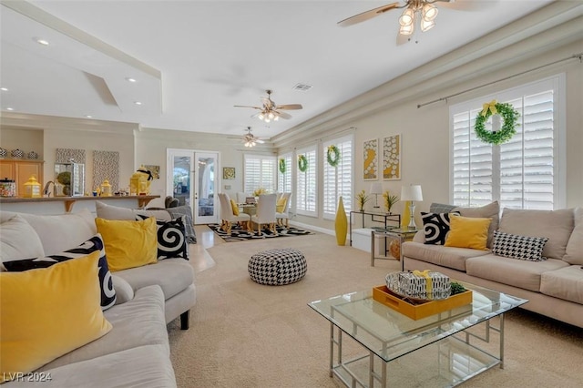 carpeted living room with ornamental molding and ceiling fan