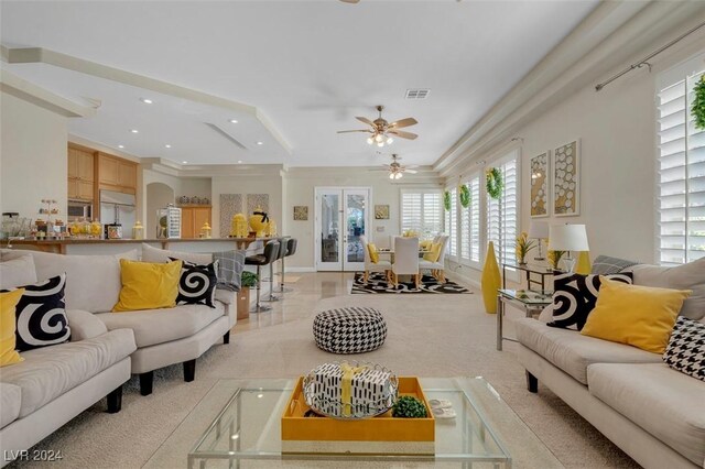 carpeted living room featuring ornamental molding, a wealth of natural light, and ceiling fan