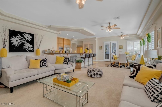 living room featuring ceiling fan, light carpet, and ornate columns