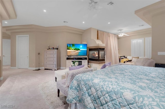 bedroom featuring ceiling fan, light colored carpet, and a multi sided fireplace