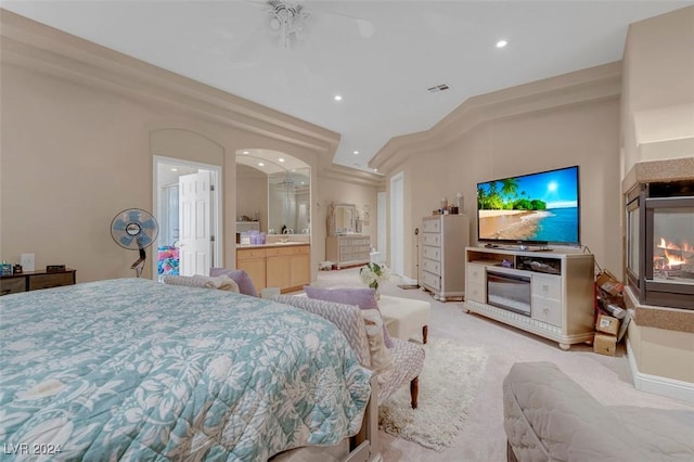 bedroom featuring a multi sided fireplace, sink, light colored carpet, and ensuite bathroom