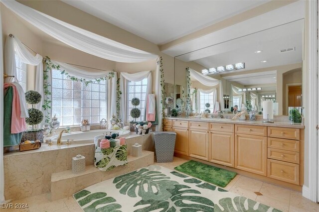 bathroom with tile patterned flooring, vanity, and tiled bath