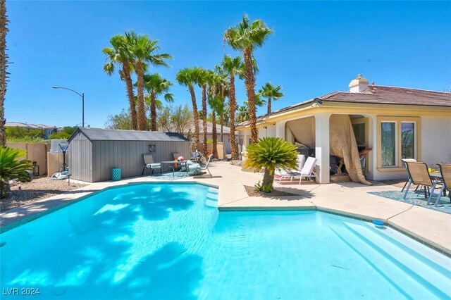 view of swimming pool with a shed and a patio area