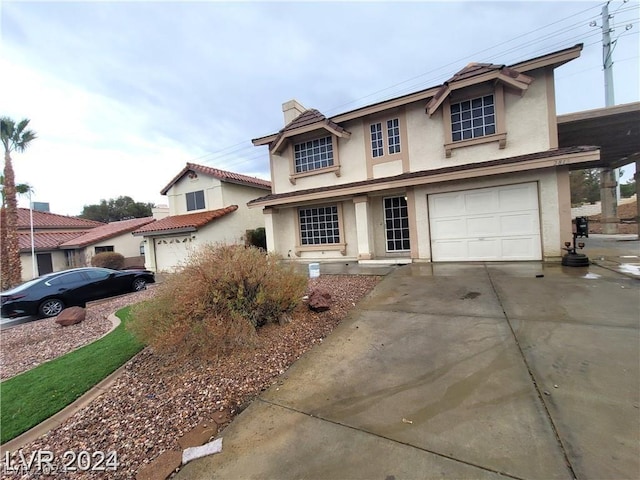 traditional-style home with stucco siding, an attached garage, a chimney, and driveway