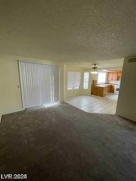 unfurnished living room with a textured ceiling, light tile patterned floors, and ceiling fan