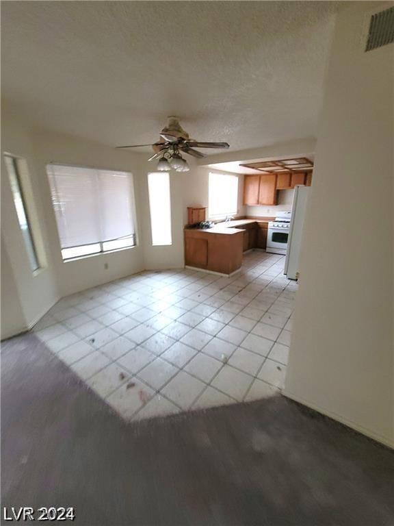 unfurnished living room with light tile patterned flooring and ceiling fan