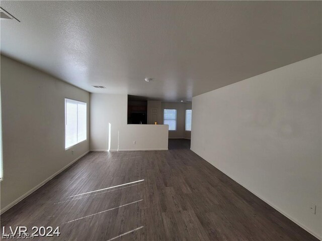 unfurnished living room featuring wood-type flooring and a textured ceiling