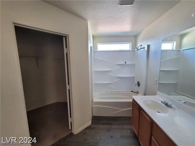 bathroom with washtub / shower combination, hardwood / wood-style floors, vanity, and a textured ceiling