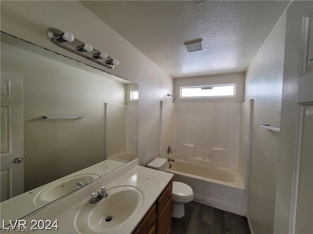 full bathroom with vanity, hardwood / wood-style floors, shower / bathing tub combination, toilet, and a textured ceiling