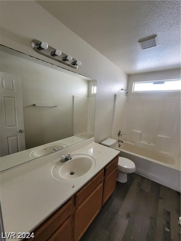 full bathroom featuring bathtub / shower combination, a textured ceiling, toilet, vanity, and hardwood / wood-style flooring