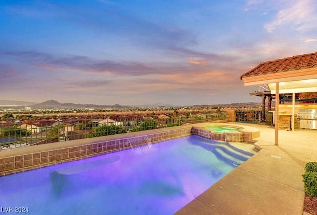 pool at dusk featuring a mountain view, an in ground hot tub, a patio, and grilling area