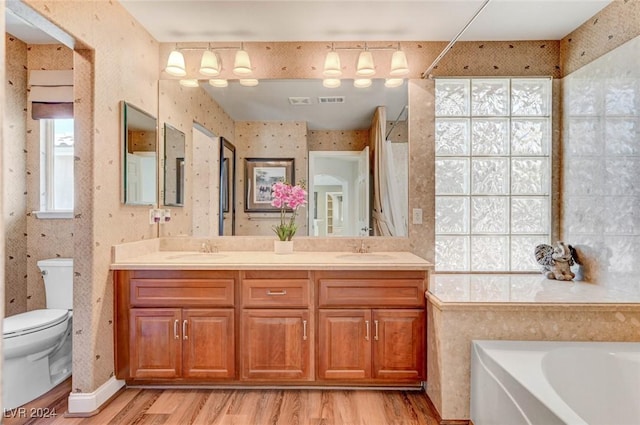 bathroom with a sink, toilet, a bath, and wallpapered walls