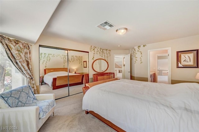 bedroom with visible vents, carpet floors, a closet, and ensuite bathroom