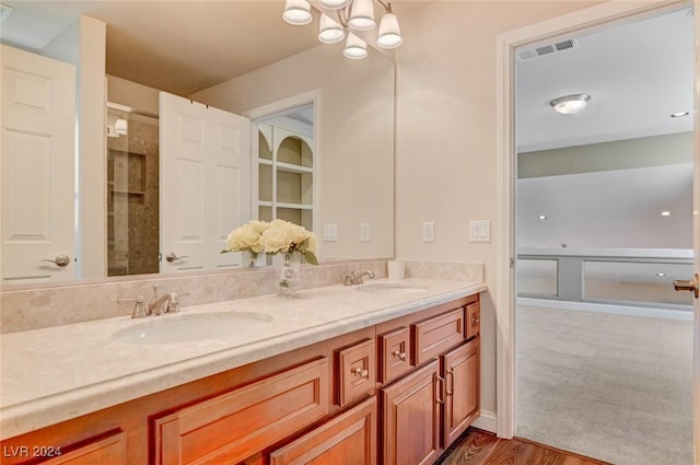 bathroom with a sink, visible vents, a notable chandelier, and double vanity