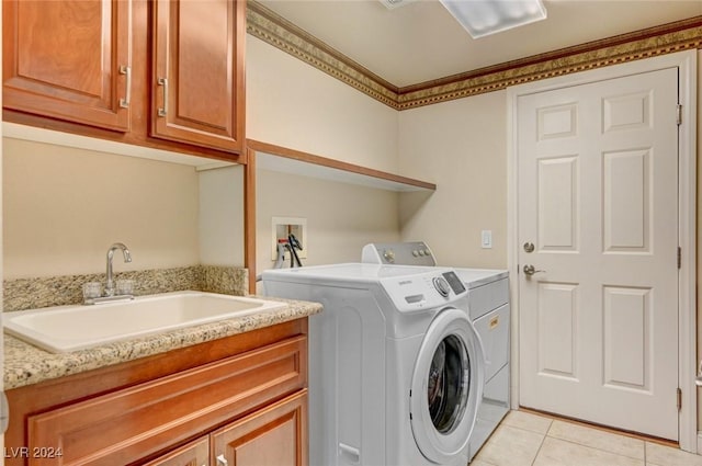 washroom with washing machine and clothes dryer, light tile patterned floors, cabinet space, and a sink