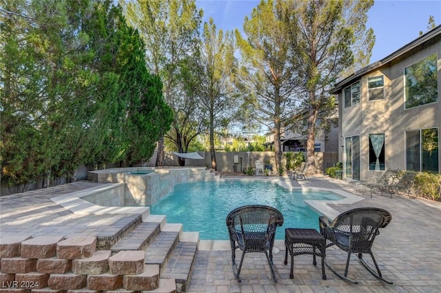 view of pool with a patio area, fence, and a pool with connected hot tub