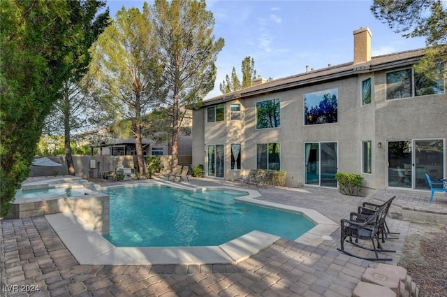 view of swimming pool featuring a patio area, a pool with connected hot tub, and fence