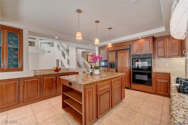 kitchen with a kitchen island, a raised ceiling, black appliances, and hanging light fixtures