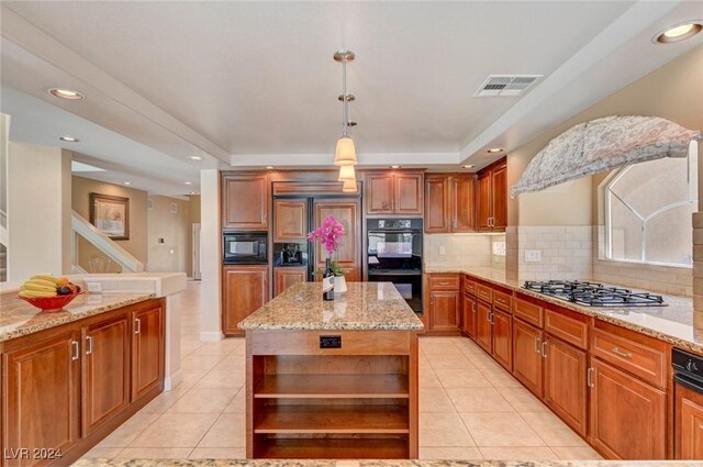 kitchen with black appliances, hanging light fixtures, light stone countertops, a kitchen island, and backsplash