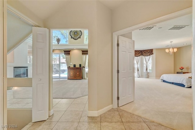 hallway with light carpet, visible vents, lofted ceiling, and light tile patterned flooring