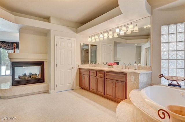 full bathroom featuring a multi sided fireplace, double vanity, a garden tub, and a sink