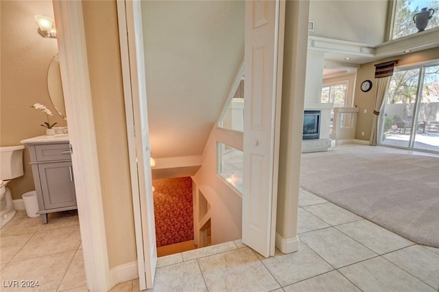 stairway featuring a glass covered fireplace, tile patterned floors, carpet flooring, and baseboards