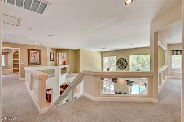 corridor with visible vents, an upstairs landing, and carpet