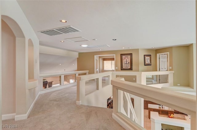 hallway featuring visible vents, an upstairs landing, recessed lighting, arched walkways, and carpet flooring