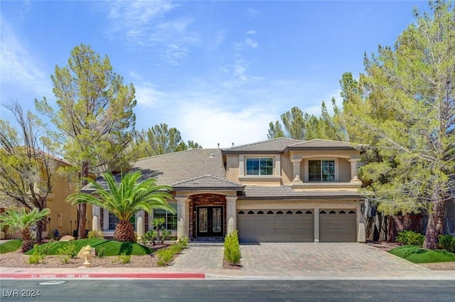 view of front of house with stucco siding, french doors, decorative driveway, and a garage