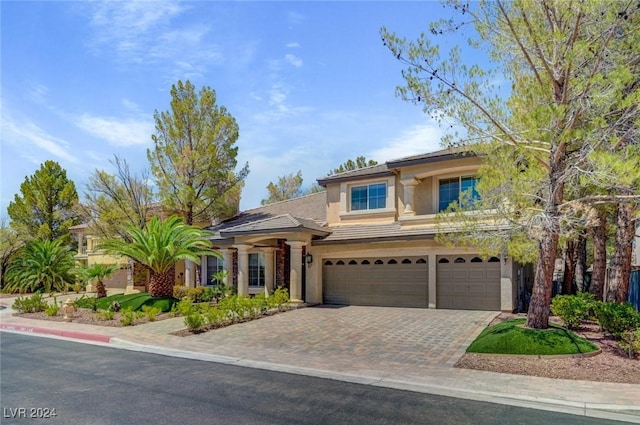 view of front of house with decorative driveway, a garage, and stucco siding