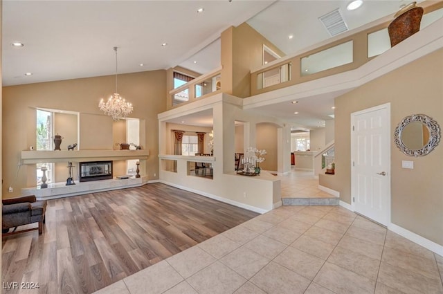 living area featuring tile patterned floors, a glass covered fireplace, a healthy amount of sunlight, and high vaulted ceiling