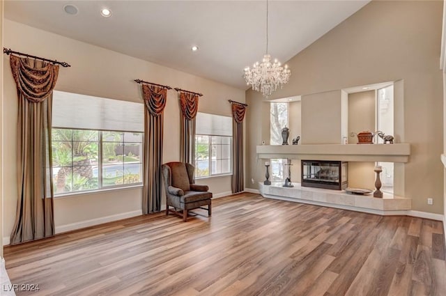 sitting room with a notable chandelier, high vaulted ceiling, a fireplace, and wood-type flooring