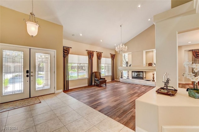 tiled entrance foyer with french doors, an inviting chandelier, and high vaulted ceiling