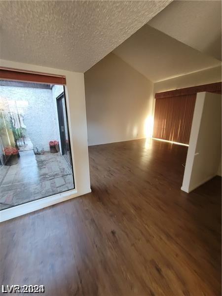 interior space featuring dark wood-type flooring, lofted ceiling, and a textured ceiling