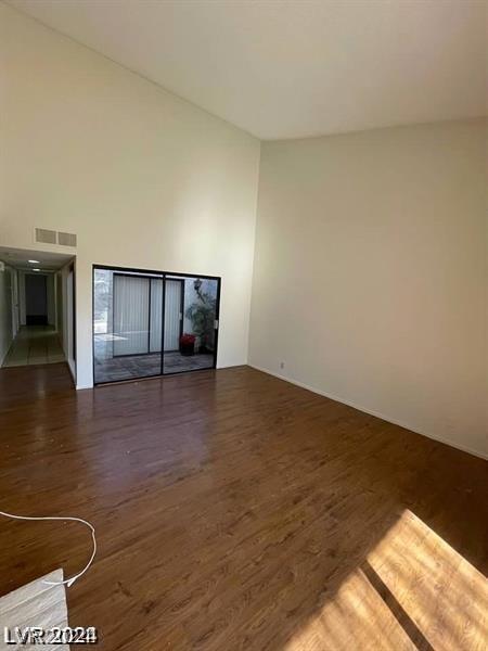 unfurnished living room with dark wood-type flooring and a towering ceiling