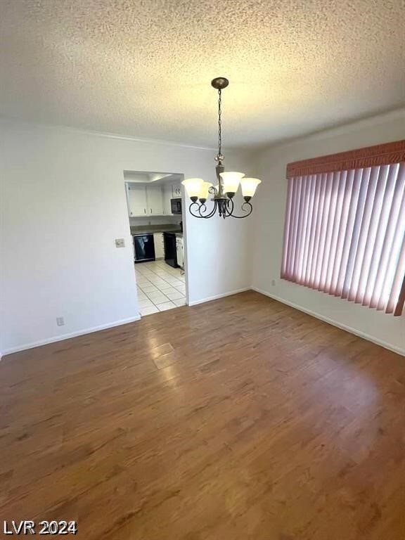 unfurnished dining area featuring a notable chandelier, light tile patterned floors, and a textured ceiling