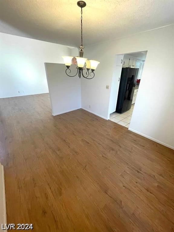 unfurnished dining area featuring a chandelier, a textured ceiling, and light tile patterned floors