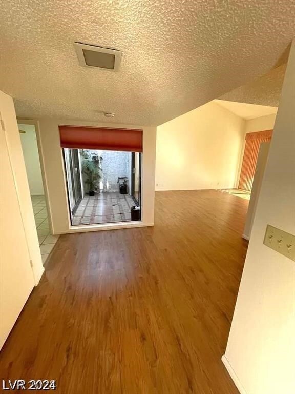 interior space with a textured ceiling and hardwood / wood-style flooring