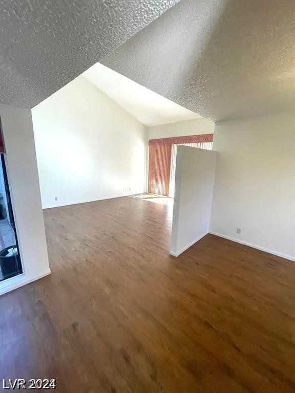 bonus room with dark hardwood / wood-style floors and a textured ceiling