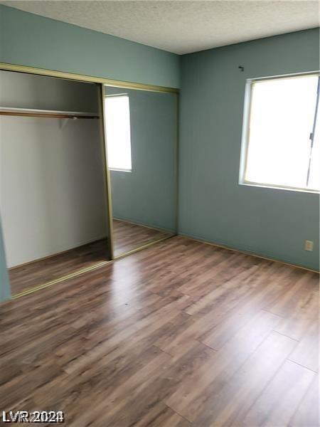 unfurnished bedroom featuring a textured ceiling, a closet, and wood-type flooring