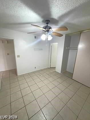 unfurnished bedroom with a closet, light tile patterned floors, and ceiling fan