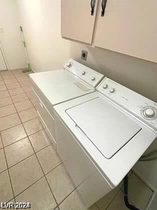 clothes washing area with light tile patterned flooring and separate washer and dryer