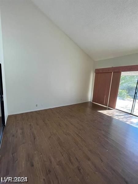 unfurnished living room featuring dark wood-type flooring, vaulted ceiling, and a textured ceiling